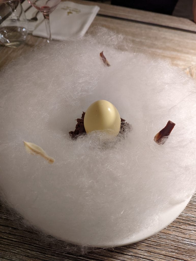 Le célèbre dessert signature "L'œuf de l'oie" dans son nid de barbe à papa au restaurant Szara Gęś w Kuchni, une adresse incontournable où manger à Cracovie.