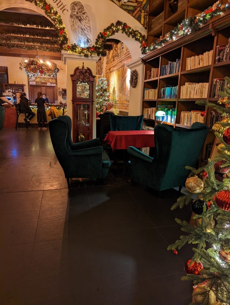 Intérieur cosy du Ministerstwo Tajemnic avec fauteuils en velours, sapin de Noël et ambiance tamisée pour sortir à Cracovie.