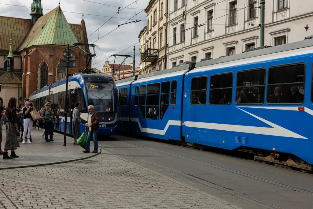 Tramways bleus modernes circulant près de la Vieille Ville, illustrant comment utiliser les transports en commun à Cracovie.